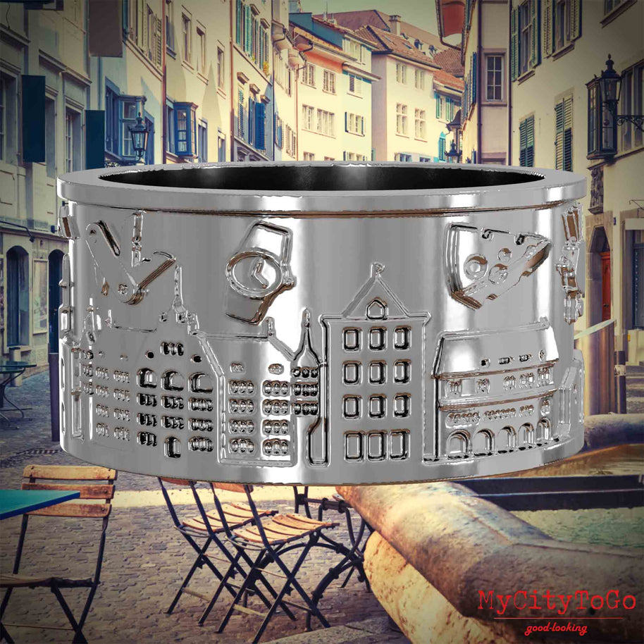 Silberner Ring mit Reliefs bekannter Sehenswürdigkeiten der Stadt Zuerich. Den Hintergrund bildet eine Ansicht der Stadt Zuerich.