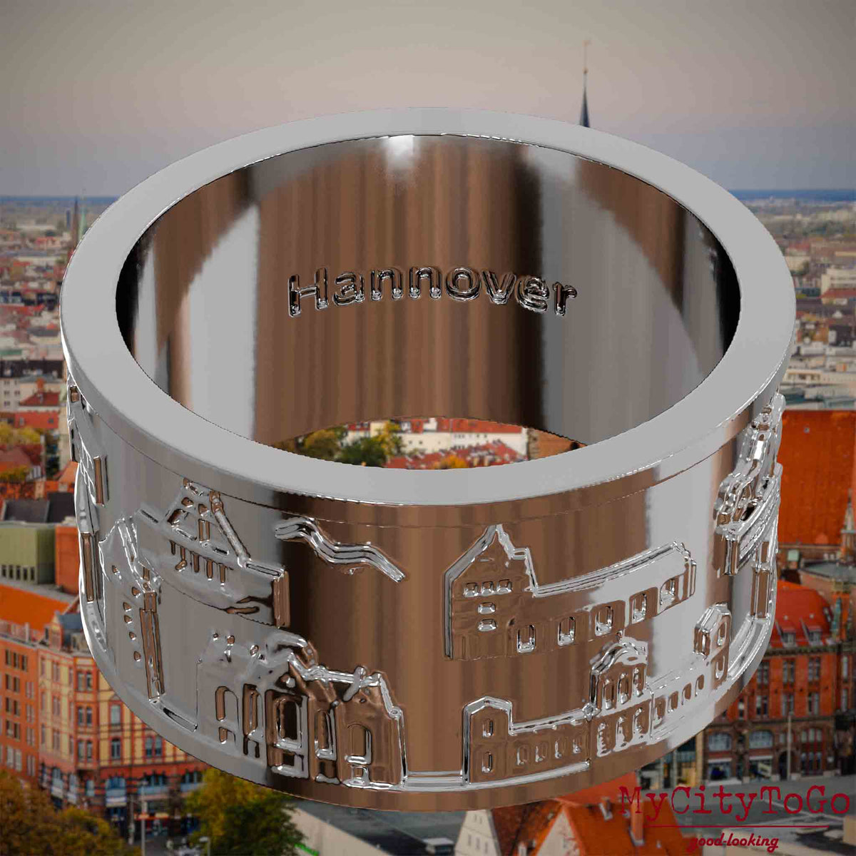 Versilberter Ring mit Reliefs bekannter Sehenswürdigkeiten der Stadt Hannover und einer Gravur des Stadtnamens auf der Innenseite. Den Hintergrund bildet eine Ansicht der Stadt Hannover.