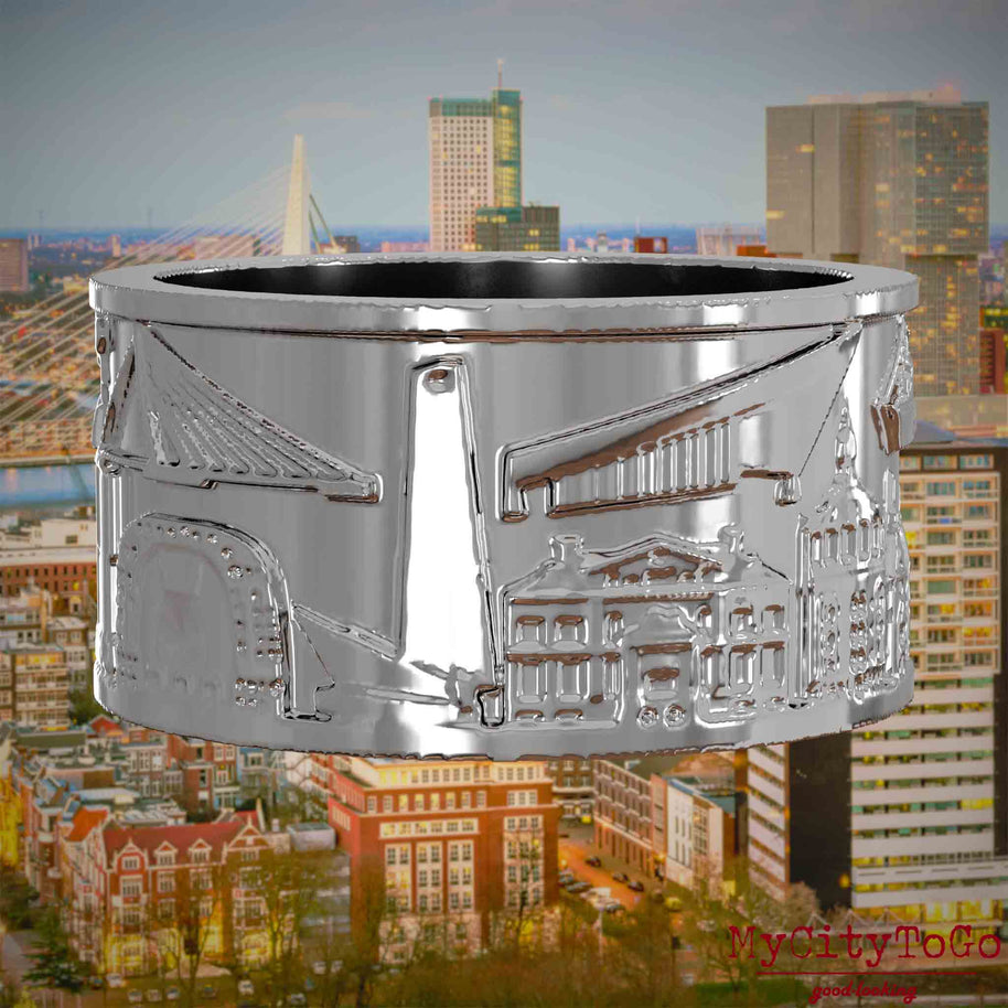 Silberner Ring mit Reliefs bekannter Sehenswürdigkeiten der Stadt Rotterdam. Den Hintergrund bildet eine Ansicht der Stadt Rotterdam.