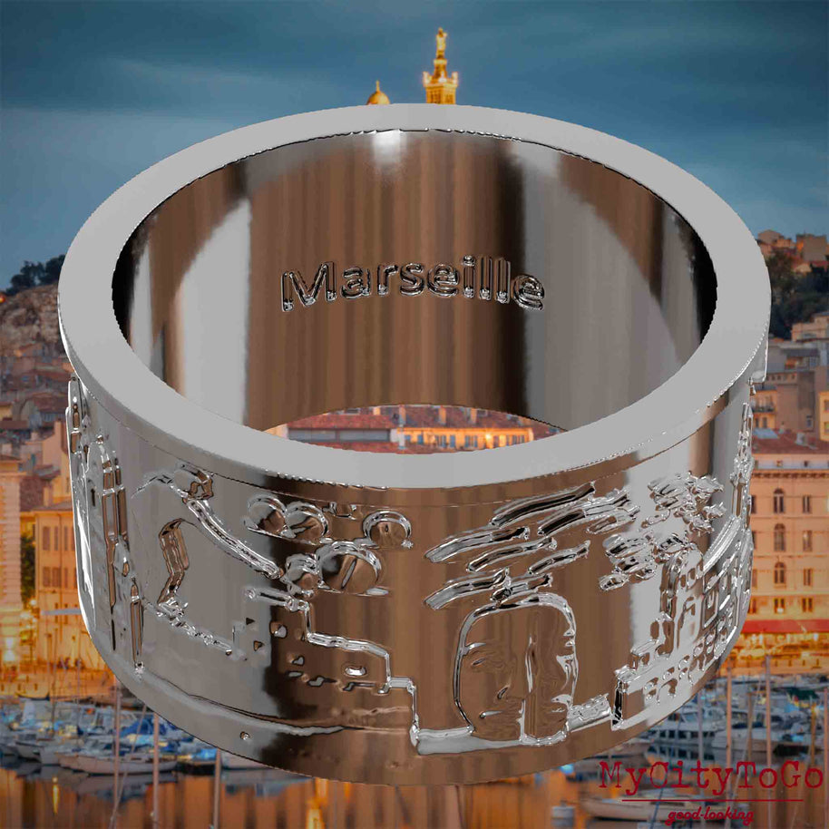Versilberter Ring mit Reliefs bekannter Sehenswürdigkeiten der Stadt Marseille und einer Gravur des Stadtnamens auf der Innenseite. Den Hintergrund bildet eine Ansicht der Stadt Marseille.