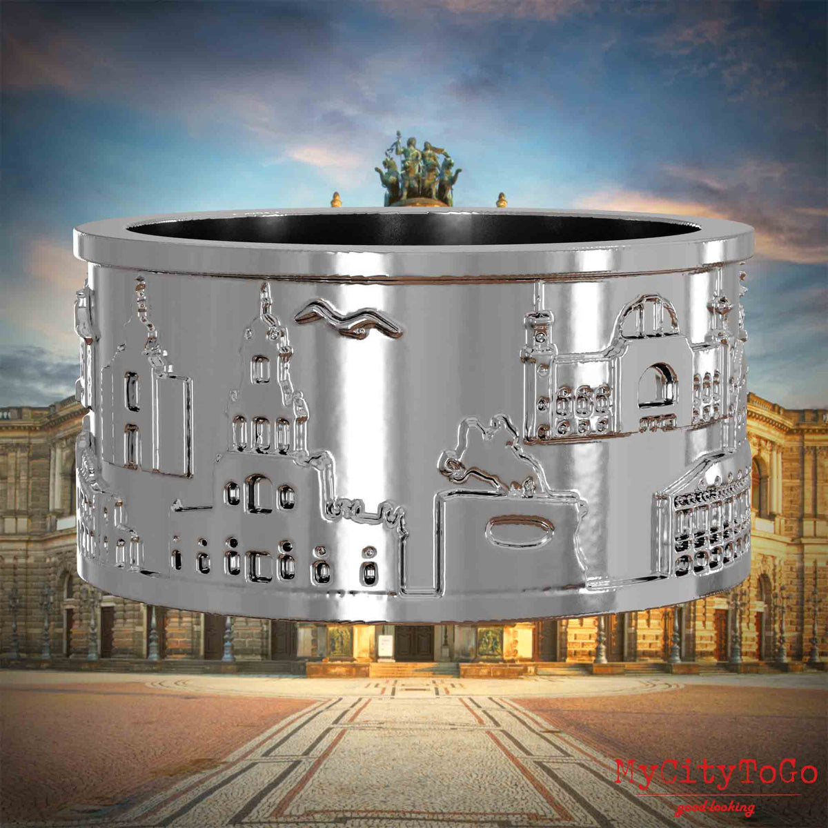 Silberner Ring mit Reliefs bekannter Sehenswürdigkeiten der Stadt Dresden. Den Hintergrund bildet eine Ansicht der Stadt Dresden.