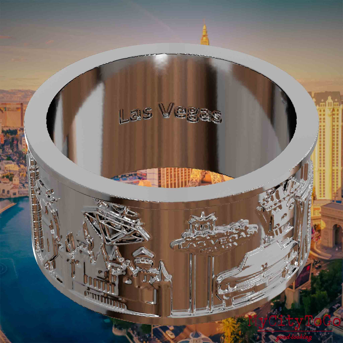 Versilberter Ring mit Reliefs bekannter Sehenswürdigkeiten der Stadt Las Vegas und einer Gravur des Stadtnamens auf der Innenseite. Den Hintergrund bildet eine Ansicht der Stadt Las Vegas.