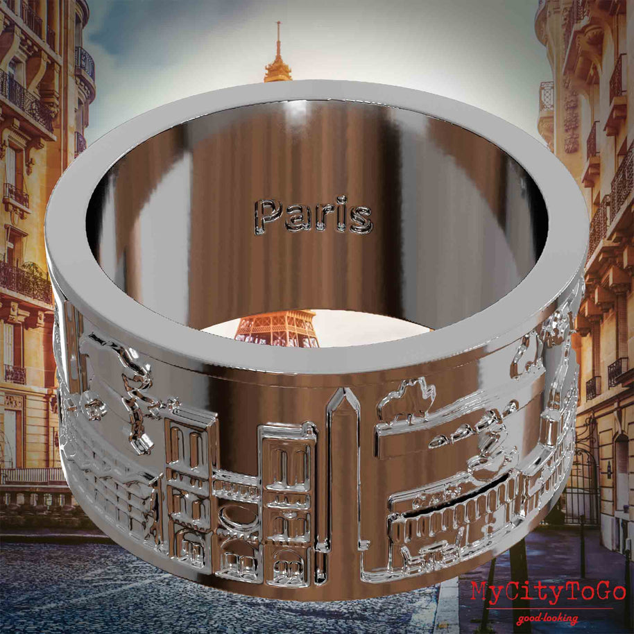 Versilberter Ring mit Reliefs bekannter Sehenswürdigkeiten der Stadt Paris und einer Gravur des Stadtnamens auf der Innenseite. Den Hintergrund bildet eine Ansicht der Stadt Paris.