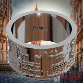 Versilberter Ring mit Reliefs bekannter Sehenswürdigkeiten der Stadt Paris und einer Gravur des Stadtnamens auf der Innenseite. Den Hintergrund bildet eine Ansicht der Stadt Paris.