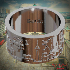 Versilberter Ring mit Reliefs bekannter Sehenswürdigkeiten der Stadt Berlin und einer Gravur des Stadtnamens auf der Innenseite.Den Hintergrund bildet eine Ansicht der Stadt Berlin.