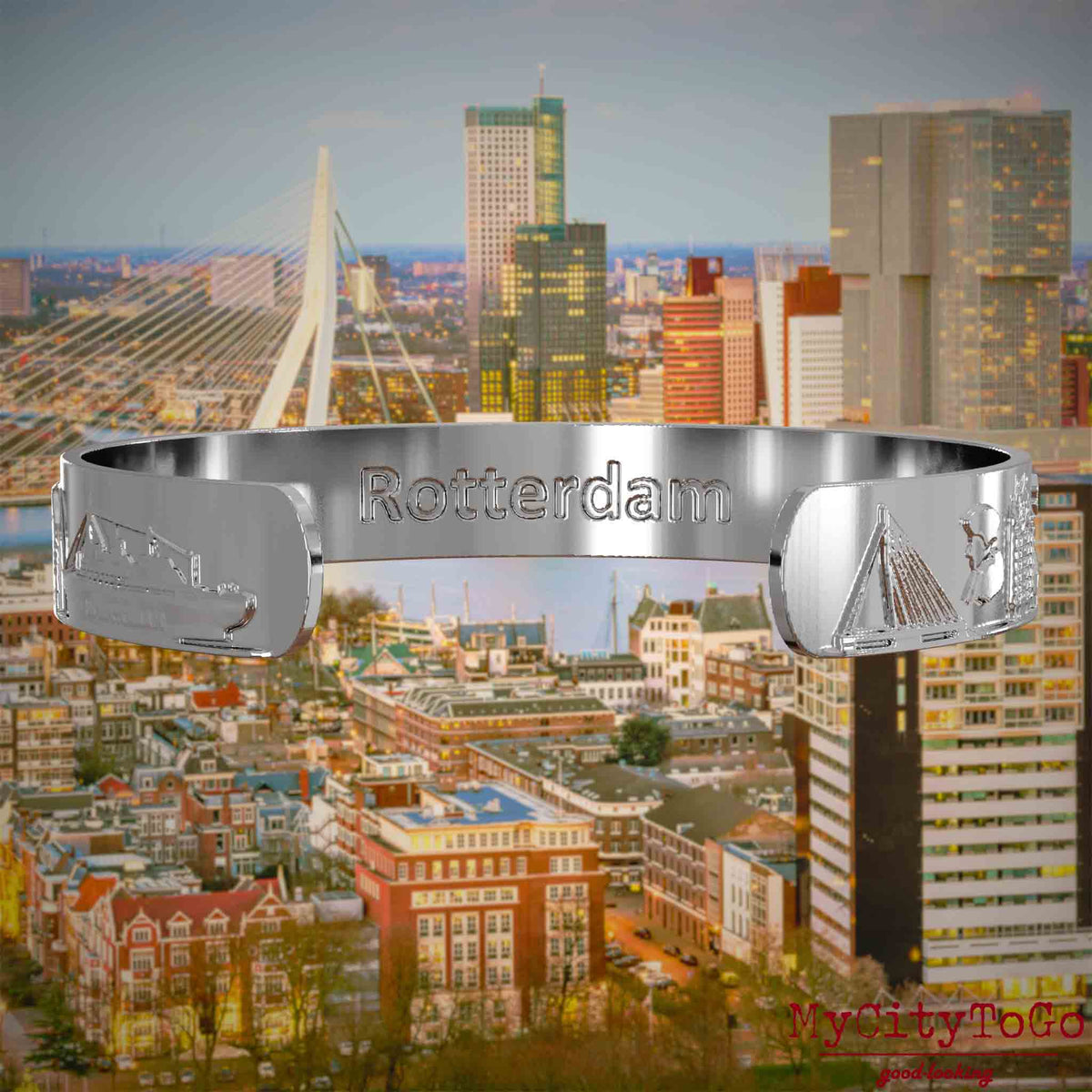 Innenseite eines silbernen Armreifs mit Reliefs bekannter Sehenswürdigkeiten der Stadt Rotterdam und einer Gravur des Stadtnamens. Den Hintergrund bildet eine Ansicht der Stadt Rotterdam.