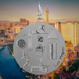 Halskette mit Drehwirbel und Vorderseite eines silbernen Schmuckanhängers, auf dem Reliefs bekannter Sehenswürdigkeiten der Stadt Las Vegas abgebildet sind. Den Hintergrund bildet eine Ansicht der Stadt Las Vegas.
