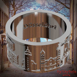 Versilberter Ring mit Reliefs bekannter Sehenswürdigkeiten der Stadt Duesseldorf und einer Gravur des Stadtnamens auf der Innenseite. Den Hintergrund bildet eine Ansicht der Stadt Duesseldorf.