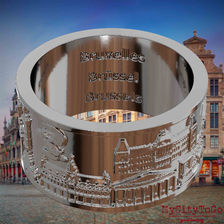Versilberter Ring mit Reliefs bekannter Sehenswürdigkeiten der Stadt Bruessel und einer Gravur des Stadtnamens auf der Innenseite. Den Hintergrund bildet eine Ansicht der Stadt Bruessel.