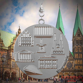 Halskette mit Drehwirbel und Rückseite eines silbernen Schmuckanhängers, auf dem Reliefs bekannter Sehenswürdigkeiten der Stadt Bremen abgebildet sind. Den Hintergrund bildet eine Ansicht der Stadt Bremen.