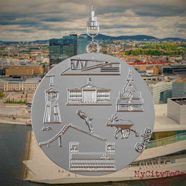 Halskette mit Drehwirbel und Vorderseite eines silbernen Schmuckanhängers, auf dem Reliefs bekannter Sehenswürdigkeiten der Stadt Oslo abgebildet sind. Den Hintergrund bildet eine Ansicht der Stadt Oslo.
