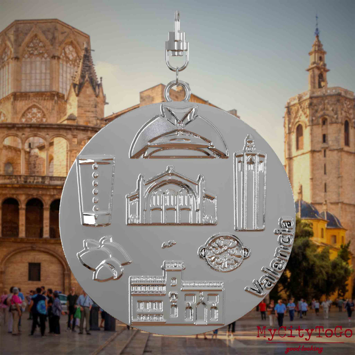 Halskette mit Drehwirbel und Vorderseite eines silbernen Schmuckanhängers, auf dem Reliefs bekannter Sehenswürdigkeiten der Stadt Valencia abgebildet sind. Den Hintergrund bildet eine Ansicht der Stadt Valencia.
