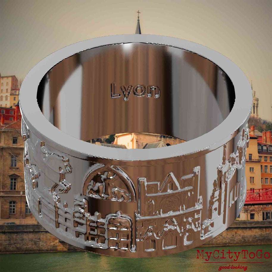 Versilberter Ring mit Reliefs bekannter Sehenswürdigkeiten der Stadt Lyon und einer Gravur des Stadtnamens auf der Innenseite. Den Hintergrund bildet eine Ansicht der Stadt Lyon.