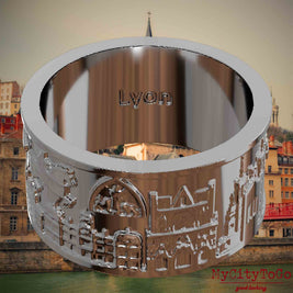 Versilberter Ring mit Reliefs bekannter Sehenswürdigkeiten der Stadt Lyon und einer Gravur des Stadtnamens auf der Innenseite. Den Hintergrund bildet eine Ansicht der Stadt Lyon.