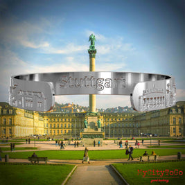 Innenseite eines silbernen Armreifs mit Reliefs bekannter Sehenswürdigkeiten der Stadt Stuttgart und einer Gravur des Stadtnamens. Den Hintergrund bildet eine Ansicht der Stadt Stuttgart.