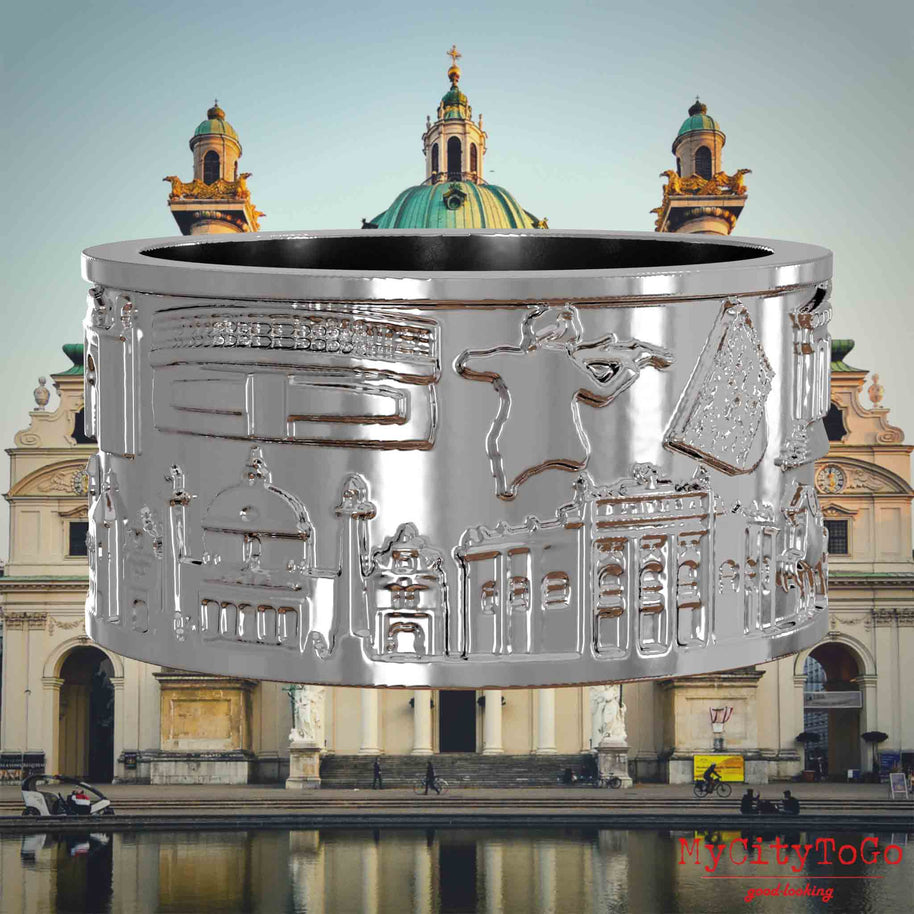 Silberner Ring mit Reliefs bekannter Sehenswürdigkeiten der Stadt Wien. Den Hintergrund bildet eine Ansicht der Stadt Wien.