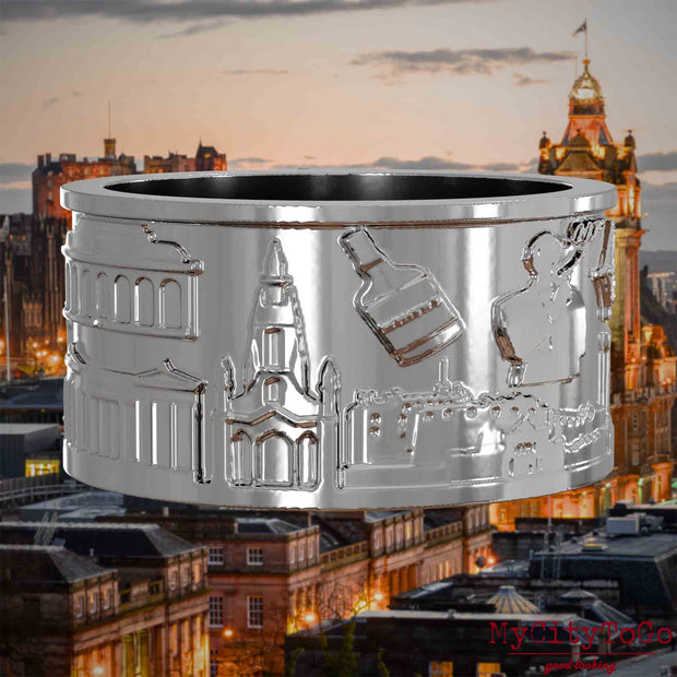 Silberner Ring mit Reliefs bekannter Sehenswürdigkeiten der Stadt Edinburgh. Den Hintergrund bildet eine Ansicht der Stadt Edinburgh.