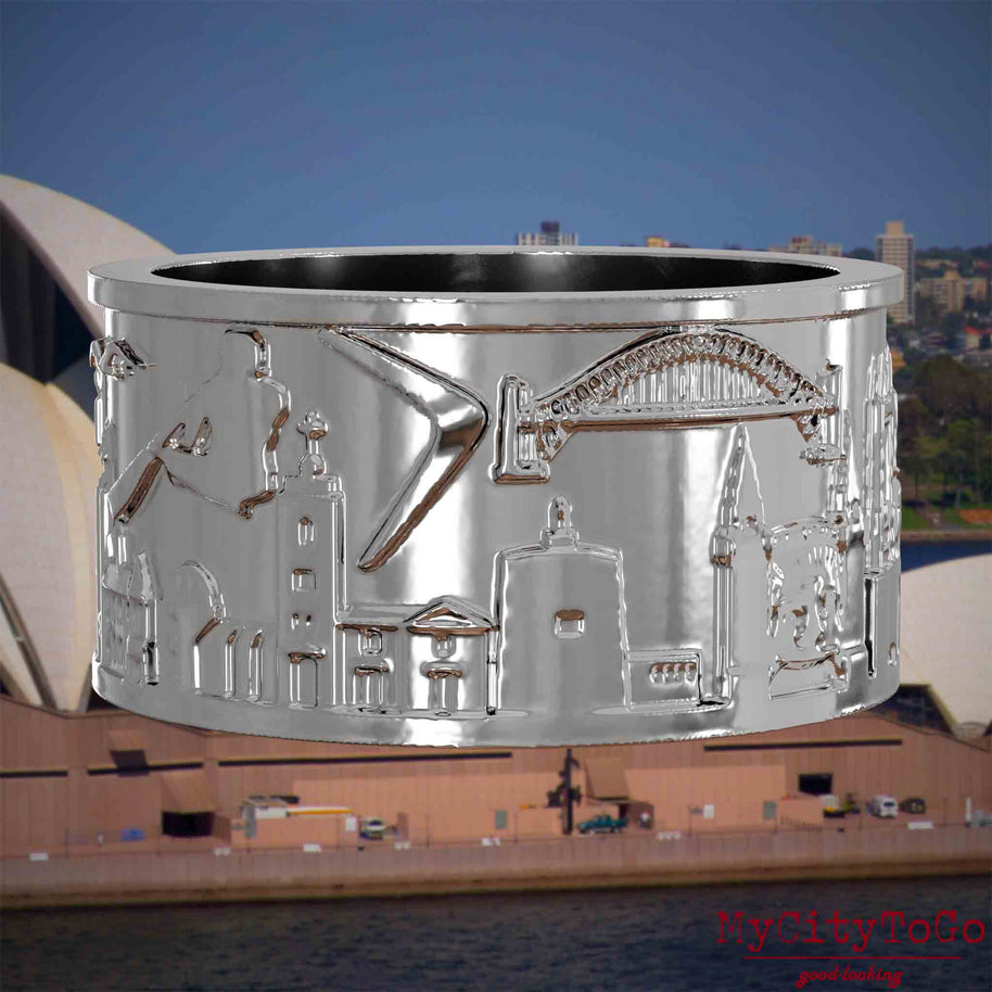 Silberner Ring mit Reliefs bekannter Sehenswürdigkeiten der Stadt Sydney. Den Hintergrund bildet eine Ansicht der Stadt Sydney.