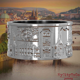 Silberner Ring mit Reliefs bekannter Sehenswürdigkeiten der Stadt Prag. Den Hintergrund bildet eine Ansicht der Stadt Prag.