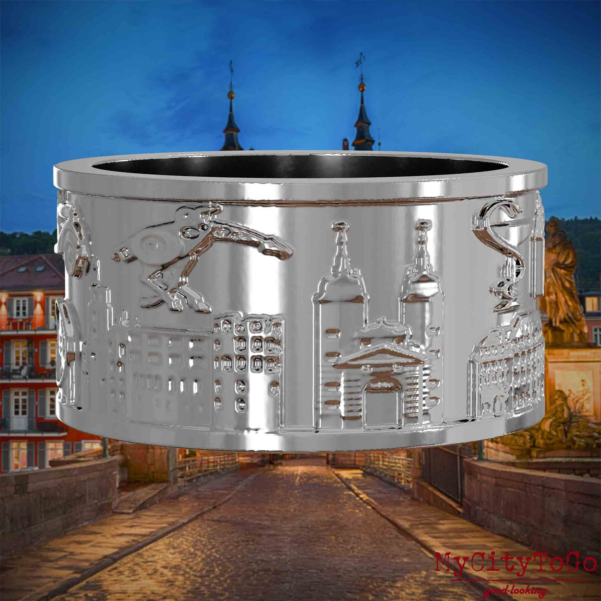 Silberner Ring mit Reliefs bekannter Sehenswürdigkeiten der Stadt Heidelberg. Den Hintergrund bildet eine Ansicht der Stadt Heidelberg.