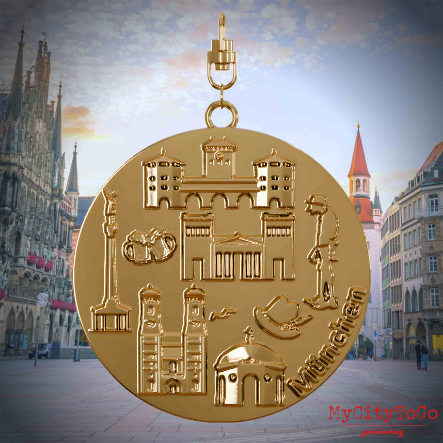 Halskette mit Drehwirbel und Vorderseite eines vergoldeten Schmuckanhängers, auf dem Reliefs bekannter Sehenswürdigkeiten der Stadt Muenchen abgebildet sind. Den Hintergrund bildet eine Ansicht der Stadt Muenchen.