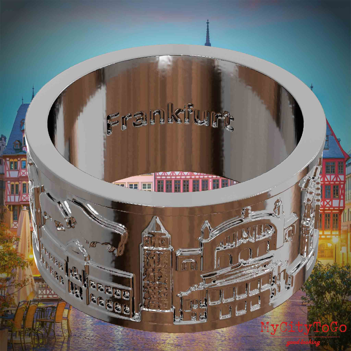 Versilberter Ring mit Reliefs bekannter Sehenswürdigkeiten der Stadt Frankfurt und einer Gravur des Stadtnamens auf der Innenseite. Den Hintergrund bildet eine Ansicht der Stadt Frankfurt.