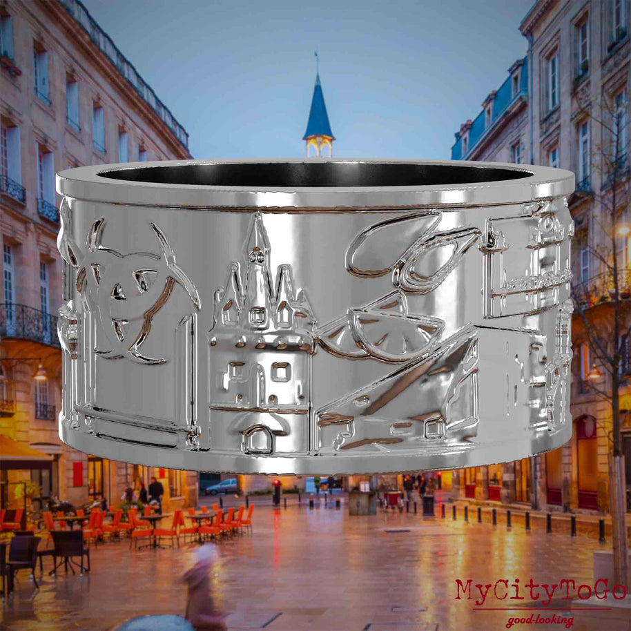 Silberner Ring mit Reliefs bekannter Sehenswürdigkeiten der Stadt Bordeaux. Den Hintergrund bildet eine Ansicht der Stadt Bordeaux.