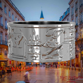 Silberner Ring mit Reliefs bekannter Sehenswürdigkeiten der Stadt Bordeaux. Den Hintergrund bildet eine Ansicht der Stadt Bordeaux.
