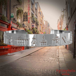 Versilberter Armreif mit Reliefs bekannter Sehenswürdigkeiten der  Stadt Dublin. Den Hintergrund bildet eine Ansicht der Stadt Dublin.