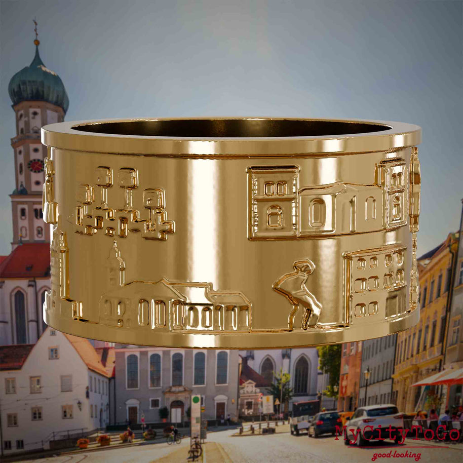 Vergoldeter Ring mit Reliefs bekannter Sehenswürdigkeiten der Stadt Augsburg. Den Hintergrund bildet eine Ansicht der Stadt Augsburg.