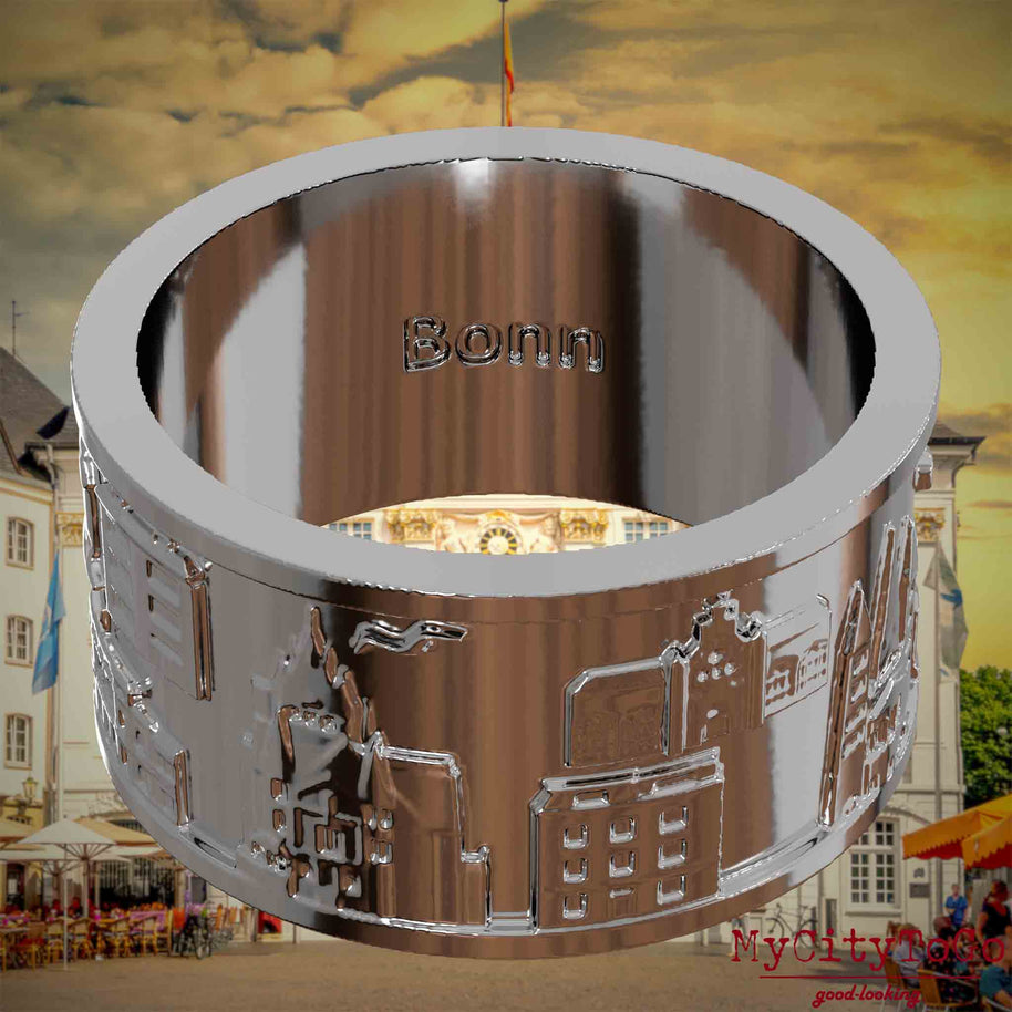 Versilberter Ring mit Reliefs bekannter Sehenswürdigkeiten der Stadt Bonn und einer Gravur des Stadtnamens auf der Innenseite. Den Hintergrund bildet eine Ansicht der Stadt Bonn.