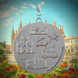 Halskette mit Drehwirbel und Rückseite eines silbernen Schmuckanhängers, auf dem Reliefs bekannter Sehenswürdigkeiten der Stadt Palma de Mallorca abgebildet sind. Den Hintergrund bildet eine Ansicht der Stadt Palma de Mallorca.
