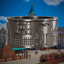 Ring aus Titan mit Reliefs bekannter Sehenswürdigkeiten der Stadt Karlsruhe. Den Hintergrund bildet eine Ansicht der Stadt Karlsruhe.
