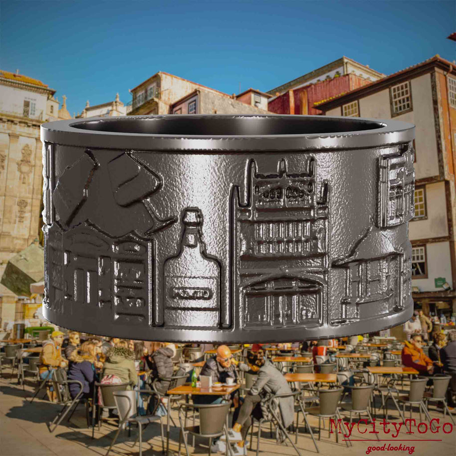 Ring aus Titan mit Reliefs bekannter Sehenswürdigkeiten der Stadt Porto. Den Hintergrund bildet eine Ansicht der Stadt Porto.