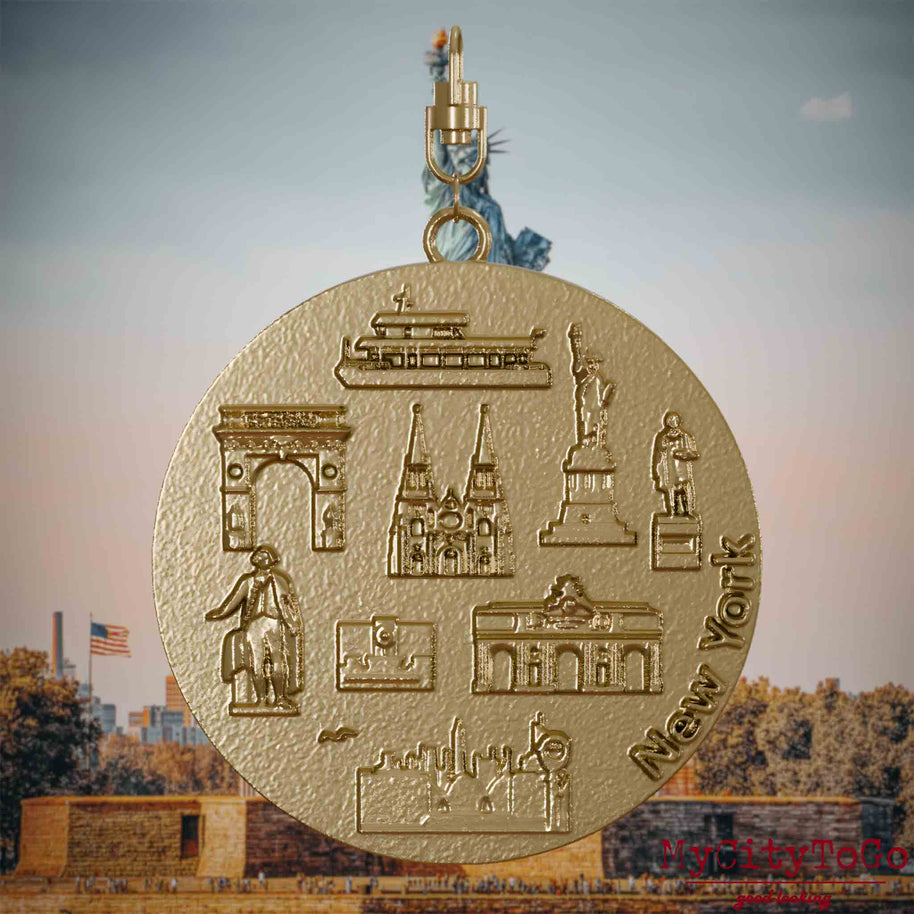 Halskette mit Drehwirbel und Vorderseite eines Schmuckanhängers aus vergoldetem Edelstahl, auf dem Reliefs bekannter Sehenswürdigkeiten der Stadt New York abgebildet sind. Den Hintergrund bildet eine Ansicht der Stadt New York.
