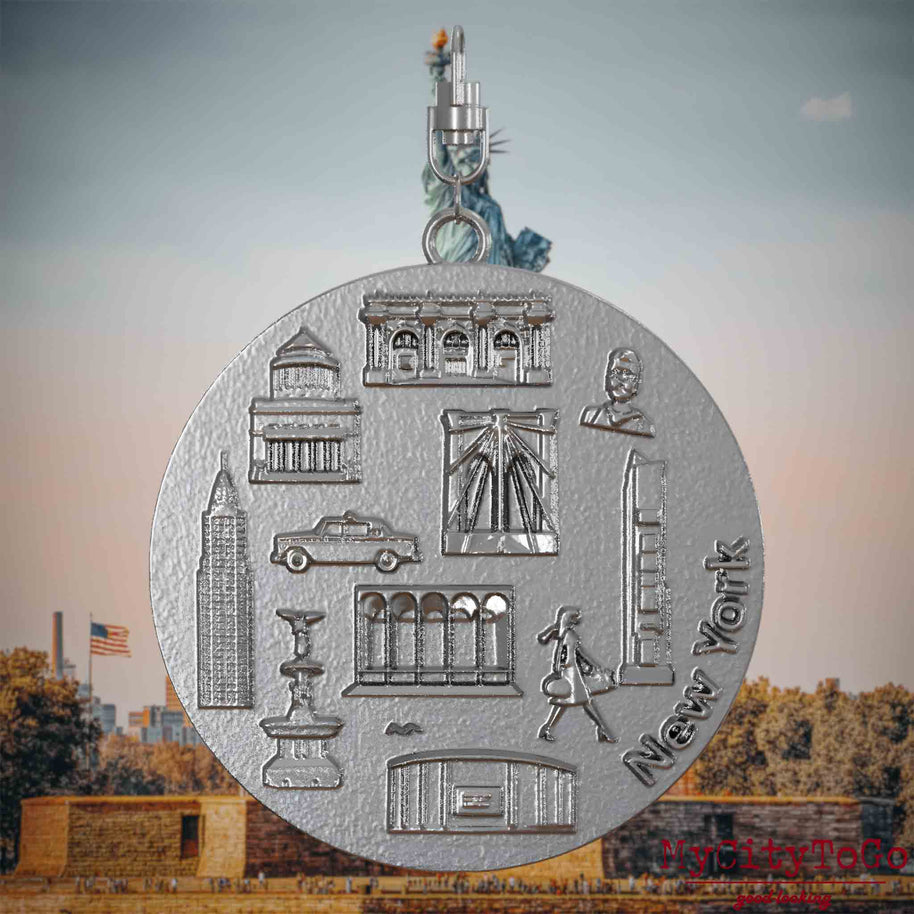 Halskette mit Drehwirbel und Rückseite eines Schmuckanhängers aus Edelstahl, auf dem Reliefs bekannter Sehenswürdigkeiten der Stadt New York abgebildet sind. Den Hintergrund bildet eine Ansicht der Stadt New York.

