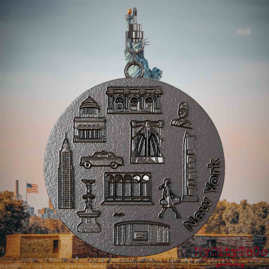 Halskette mit Drehwirbel und Rückseite eines Schmuckanhängers aus Titan, auf dem Reliefs bekannter Sehenswürdigkeiten der Stadt New York abgebildet sind. Den Hintergrund bildet eine Ansicht der Stadt New York.
