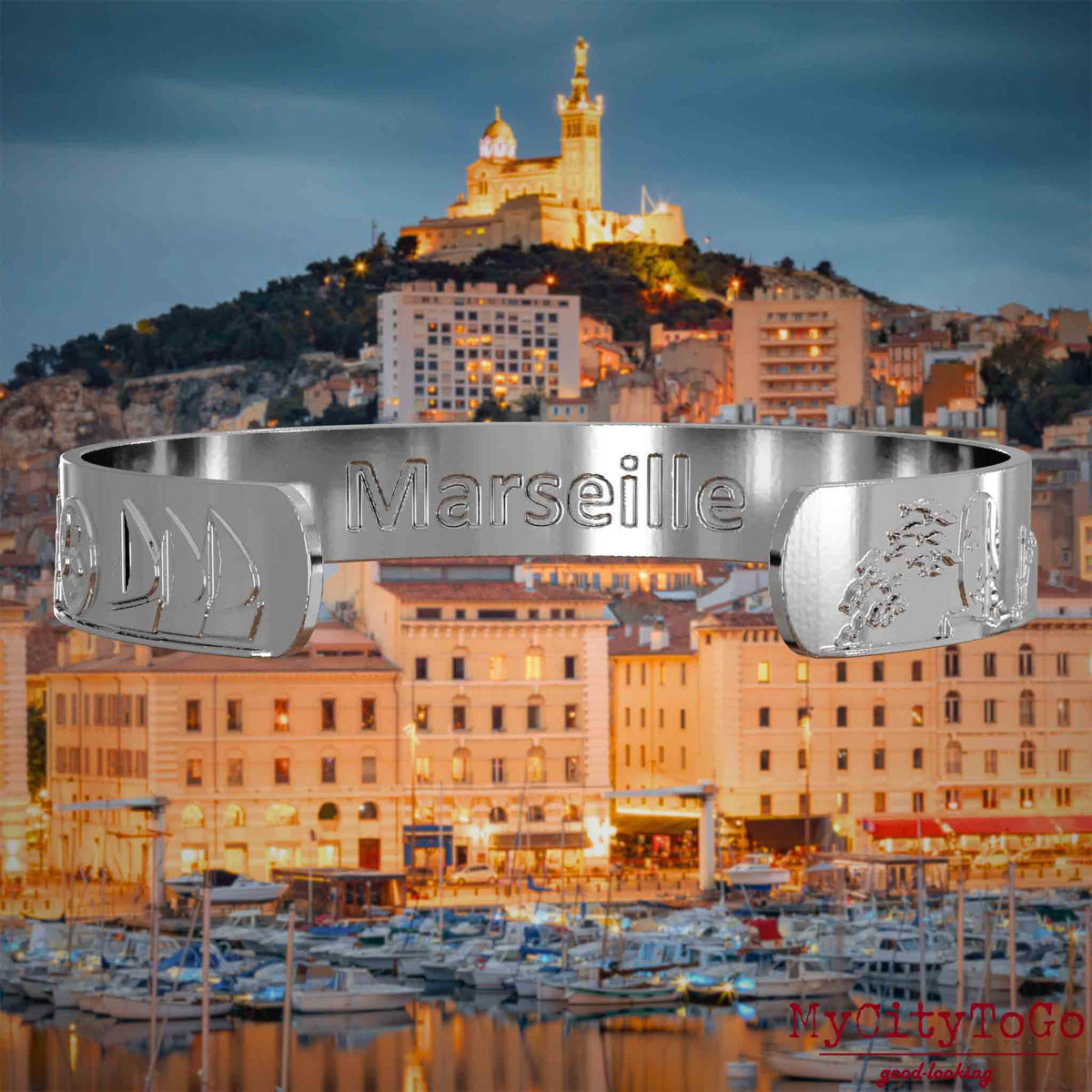 Innenseite eines silbernen Armreifs mit Reliefs bekannter Sehenswürdigkeiten der Stadt Marseille und einer Gravur des Stadtnamens. Den Hintergrund bildet eine Ansicht der Stadt Marseille.