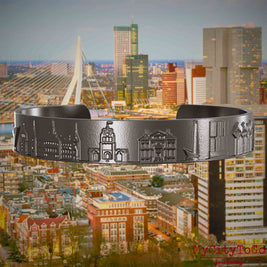 Armreif aus Titan mit Reliefs bekannter Sehenswürdigkeiten der Stadt Rotterdam. Den Hintergrund bildet eine Ansicht der Stadt Rotterdam.