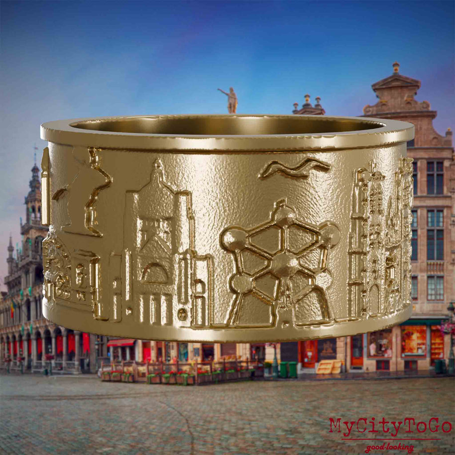Ring aus vergoldetem Edelstahl mit Reliefs bekannter Sehenswürdigkeiten der Stadt Bruessel. Den Hintergrund bildet eine Ansicht der Stadt Bruessel.