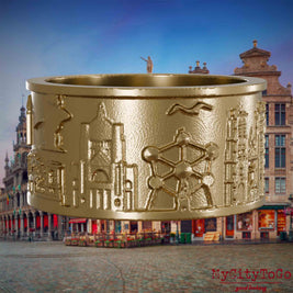 Ring aus vergoldetem Edelstahl mit Reliefs bekannter Sehenswürdigkeiten der Stadt Bruessel. Den Hintergrund bildet eine Ansicht der Stadt Bruessel.