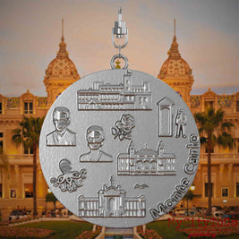 Halskette mit Drehwirbel und Rückseite eines Schmuckanhängers aus Edelstahl, auf dem Reliefs bekannter Sehenswürdigkeiten der Stadt Monte Carlo abgebildet sind. Den Hintergrund bildet eine Ansicht der Stadt Monte Carlo .
