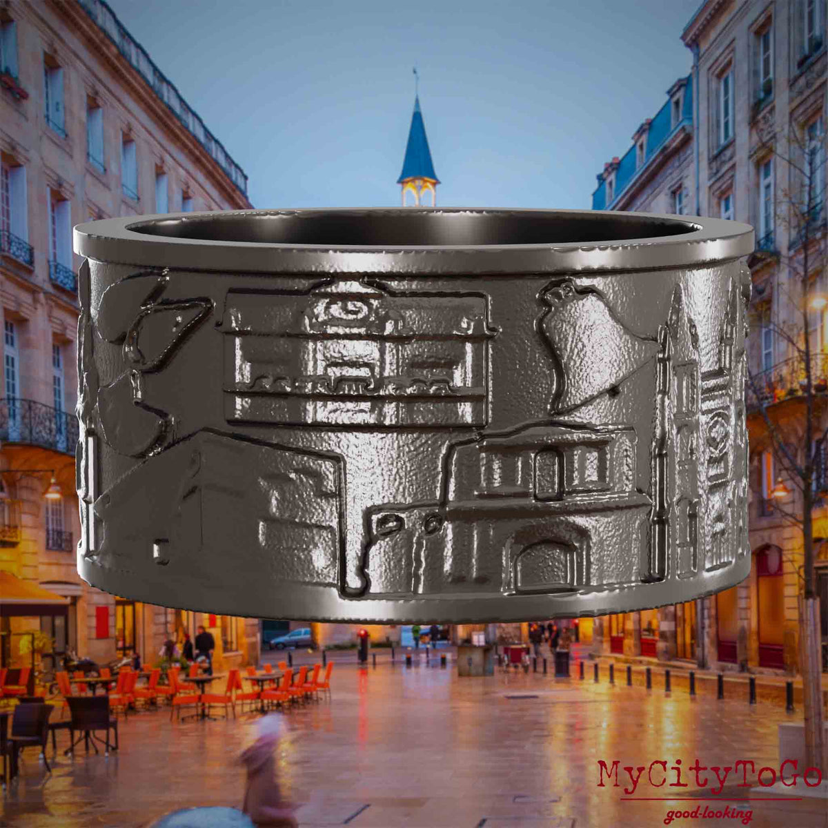 Ring aus Titan mit Reliefs bekannter Sehenswürdigkeiten der Stadt Bordeaux. Den Hintergrund bildet eine Ansicht der Stadt Bordeaux.