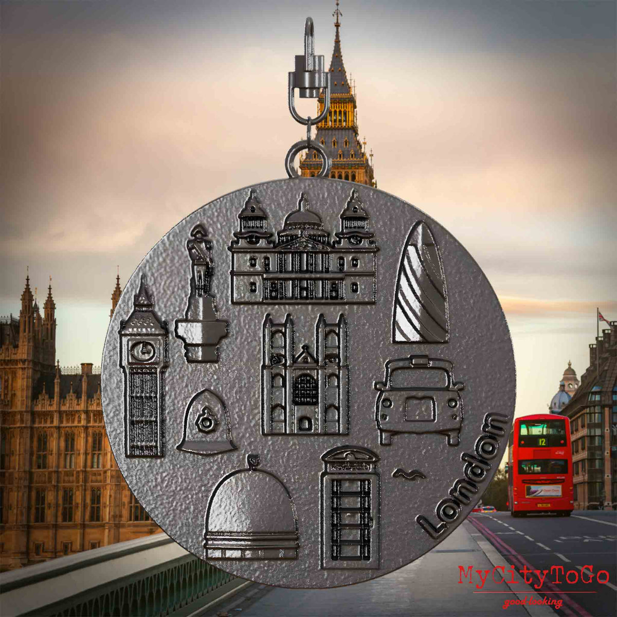 Halskette mit Drehwirbel und Rückseite eines Schmuckanhängers aus Titan, auf dem Reliefs bekannter Sehenswürdigkeiten der Stadt London abgebildet sind. Den Hintergrund bildet eine Ansicht der Stadt London.

