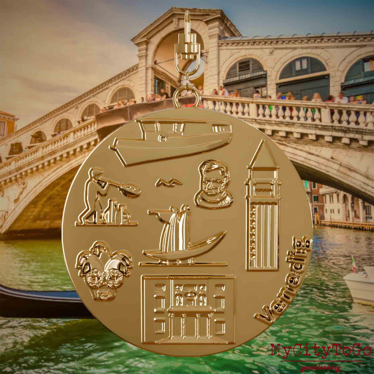 Halskette mit Drehwirbel und Rückseite eines vergoldeten Schmuckanhängers, auf dem Reliefs bekannter Sehenswürdigkeiten der Stadt Venedig abgebildet sind. Den Hintergrund bildet eine Ansicht der Stadt Venedig.

