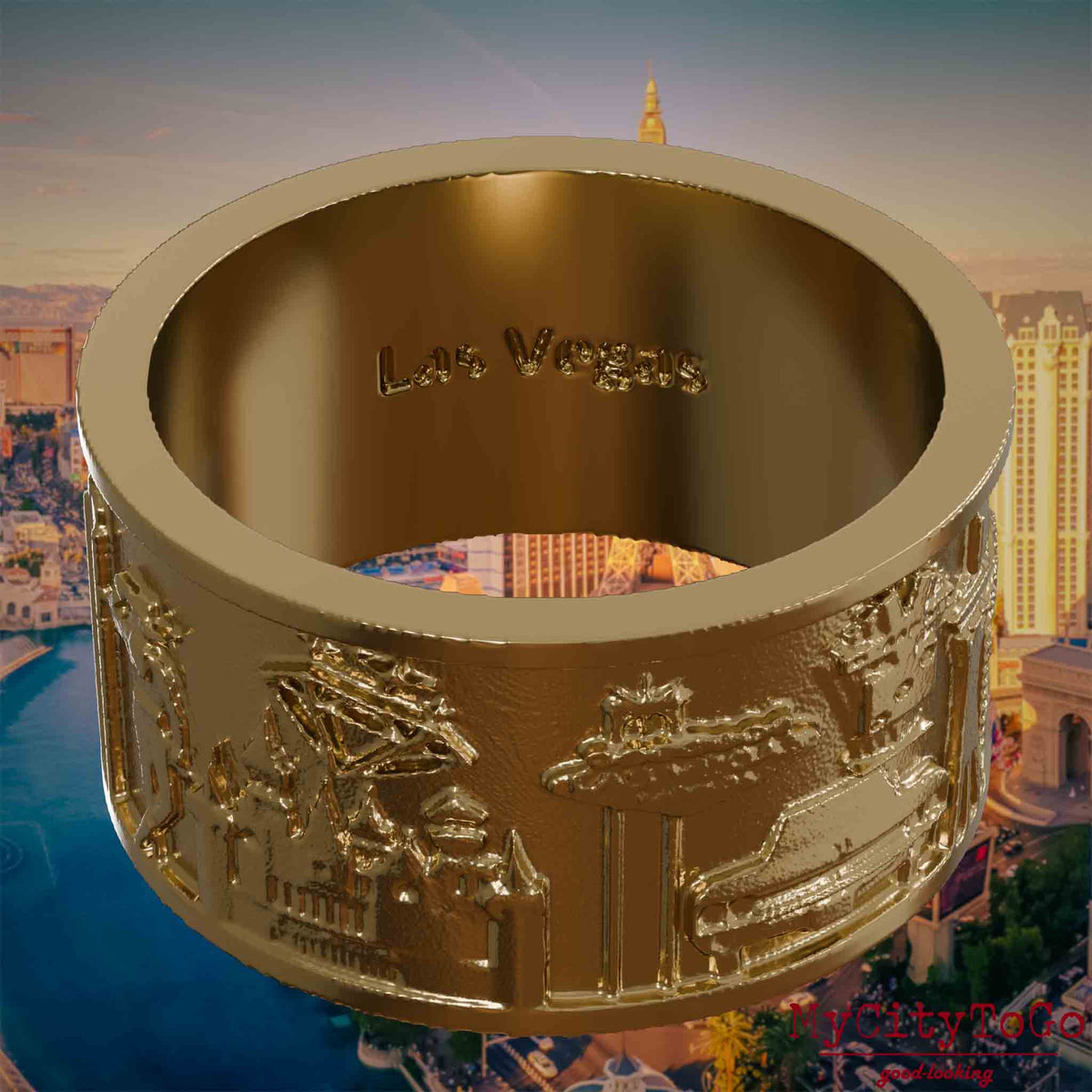 Ring aus vergoldetem Edelstahl mit Reliefs bekannter Sehenswürdigkeiten der Stadt Las Vegas und einer Gravur des Stadtnamens auf der Innenseite. Den Hintergrund bildet eine Ansicht der Stadt Las Vegas.