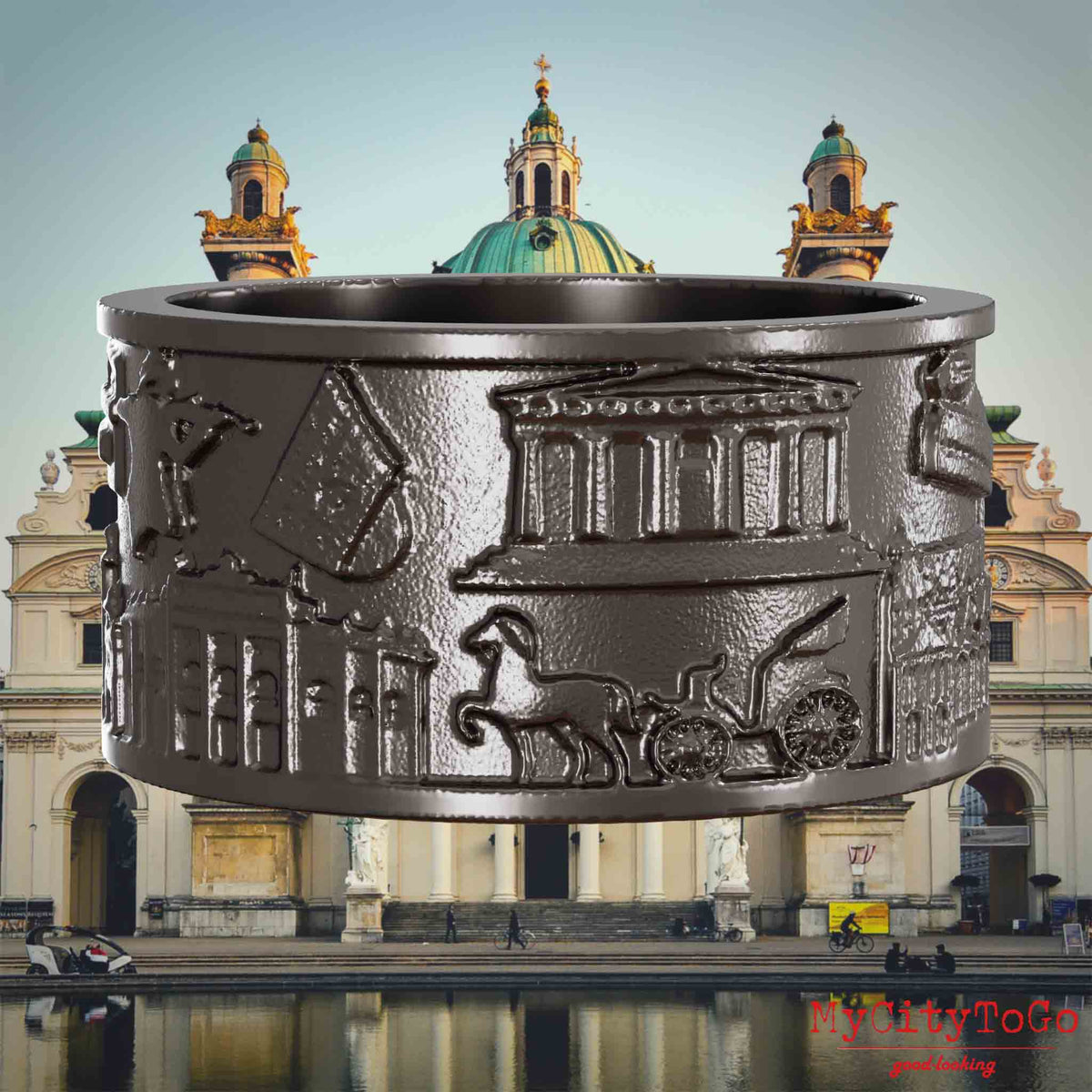 Ring aus Titan mit Reliefs bekannter Sehenswürdigkeiten der Stadt Wien. Den Hintergrund bildet eine Ansicht der Stadt Wien.