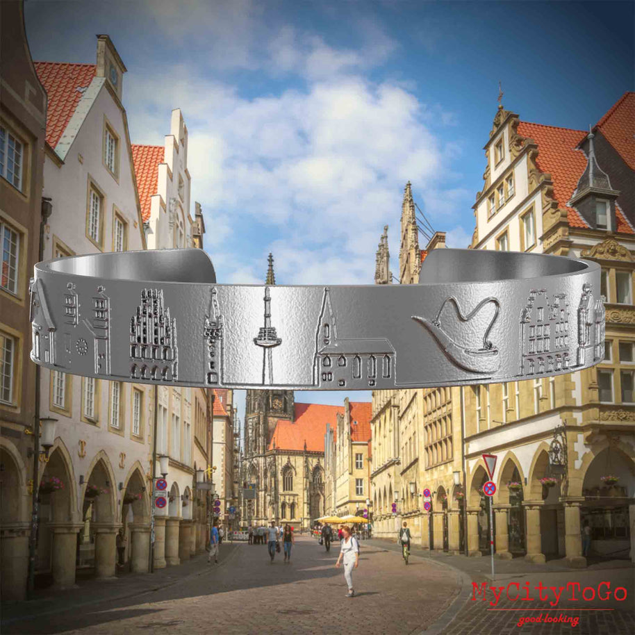 Armreif aus Edelstahl mit Reliefs bekannter Sehenswürdigkeiten der Stadt Muenster. Den Hintergrund bildet eine Ansicht der Stadt Muenster.