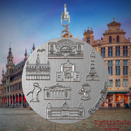 Halskette mit Drehwirbel und Vorderseite eines Schmuckanhängers aus Edelstahl, auf dem Reliefs bekannter Sehenswürdigkeiten der Stadt Bruessel abgebildet sind. Den Hintergrund bildet eine Ansicht der Stadt Bruessel.
