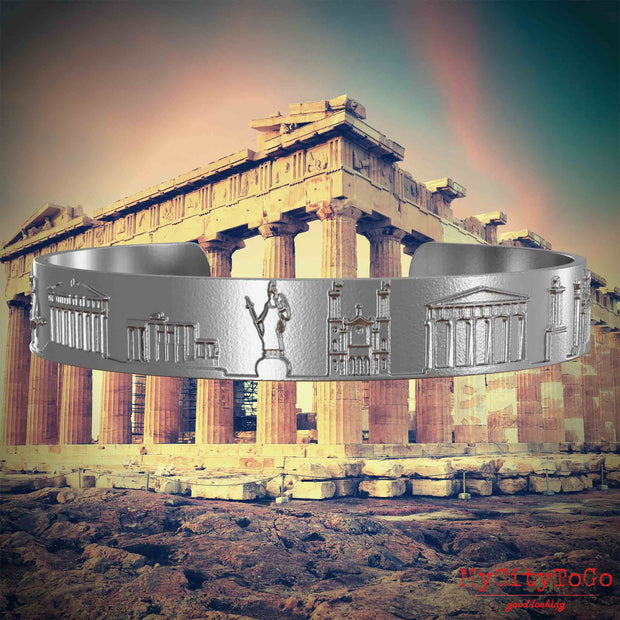Armreif aus Edelstahl mit Reliefs bekannter Sehenswürdigkeiten der Stadt Athen. Den Hintergrund bildet eine Ansicht der Stadt Athen.